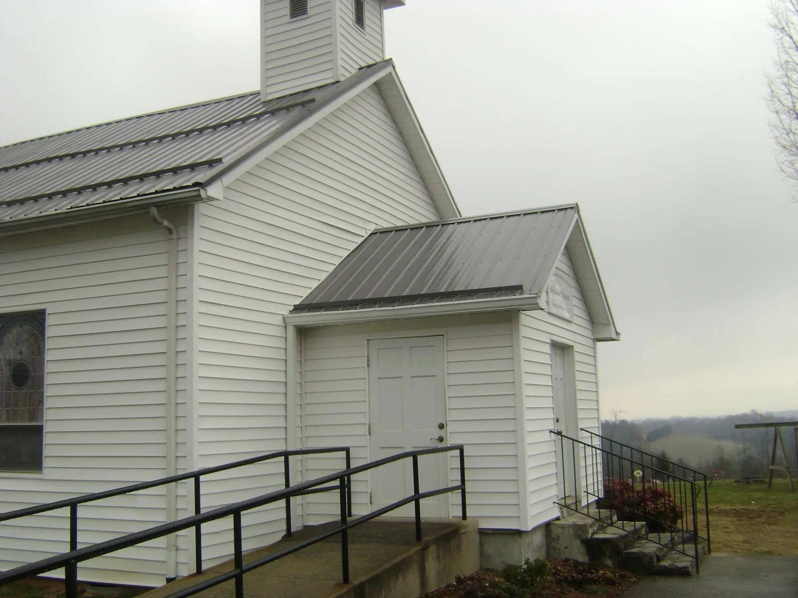 Gray metal roof on a white clapboard church with a steeple in Chandler